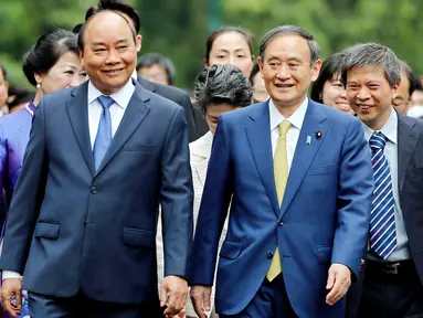 PM Jepang, Yoshihide Suga (kanan tengah) berjalan bersama dengan PM Vietnam, Nguyen Xuan Phuc (kiri depan) setibanya di Istana Kepresidenan, di Hanoi, Vietnam, Senin (19/10/2020). Yoshihide Suga melakukan kunjungan resmi ke Vietnam hingga 20 Oktober 2020.  (AP Photo/Minh Hoang, Pool)