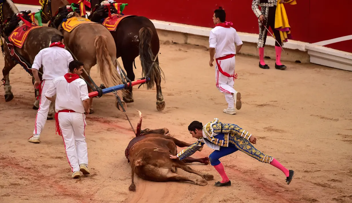 Matador Spanyol Cayetano menyentuh banteng yang mati usai bertarung dalam Festival San Fermin, Pamplona, Spanyol, Jumat (12/7/2019). (AP Photo/Alvaro Barrientos)