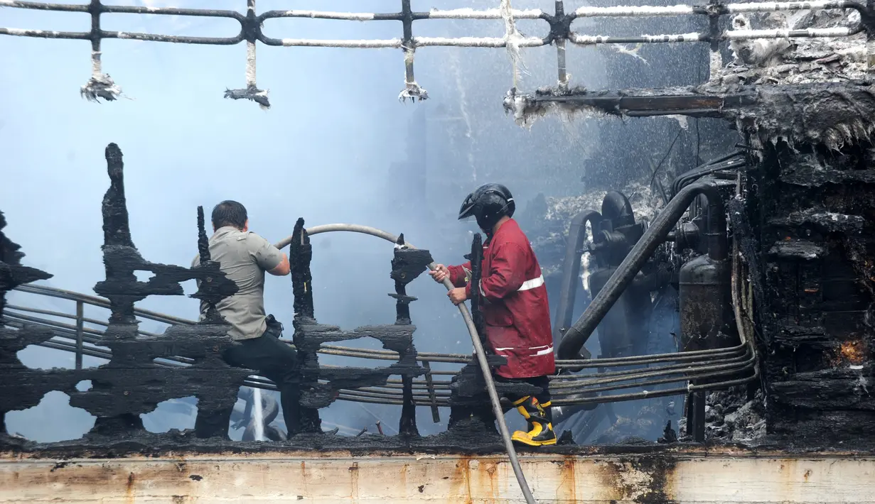 Aparat kepolisian mencoba memadamkan api di kapal nelayan di Pelabuhan Benoa, Denpasar, Bali, Senin (9/7). Polisi masih menyelidiki jumlah kerugian akibat kebakaran. (SONNY TUMBELAKA/AFP)