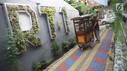 Pedagang melintas di salah satu gang kampung hijau di kawasan Malakasari, Jakarta, Sabtu (15/9). Tingginya kesadaran masyarakat akan pentingnya tumbuhan membuat kawasan tersebut terlihat asri dan dipenuhi berbagai tanaman. (Liputan6.com/Immanuel Antonius)