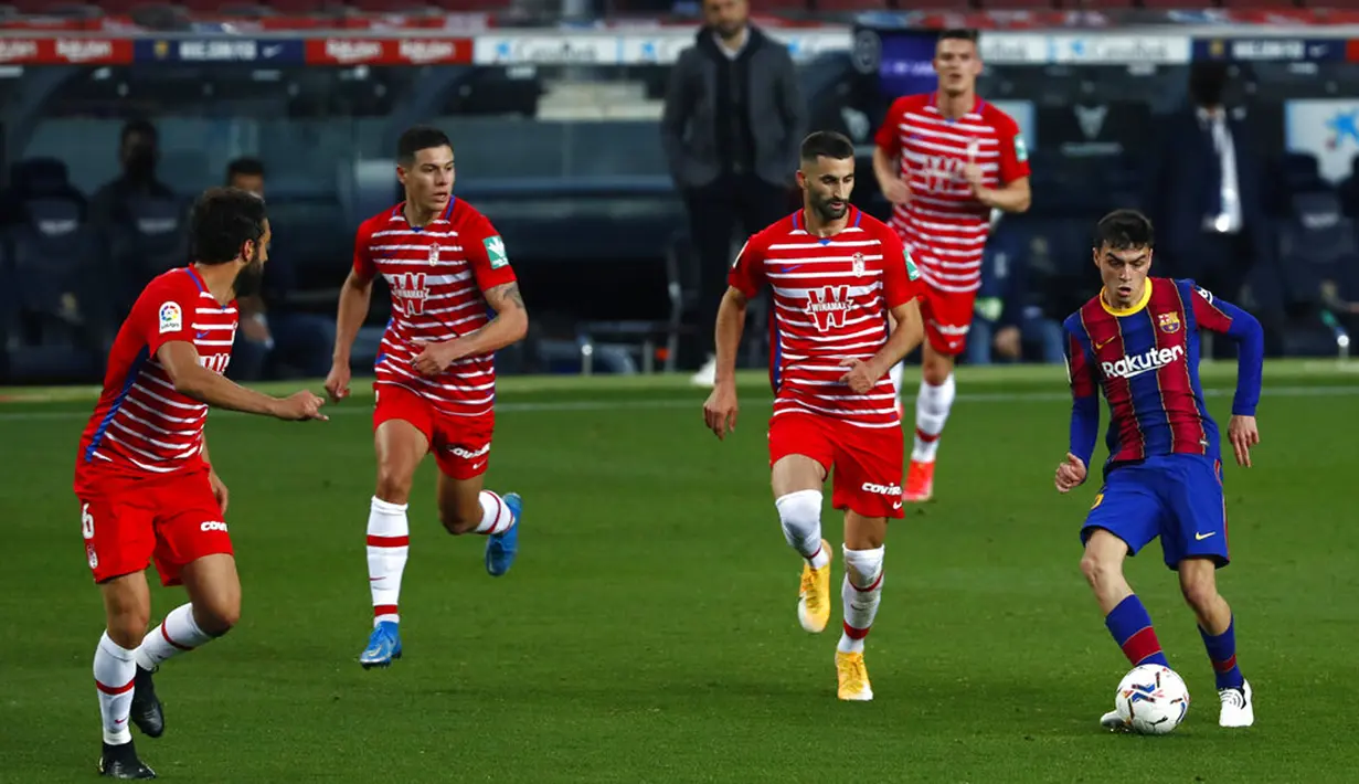 Pemain Barcelona Pedri (kanan) mengoper bola melewati pemain Granada pada pertandingan La Liga di Stadion Camp Nou, Barcelona, Spanyol, Kamis (29/4/2021). Barcelona kalah 1-2. (AP Photo/Joan Monfort)