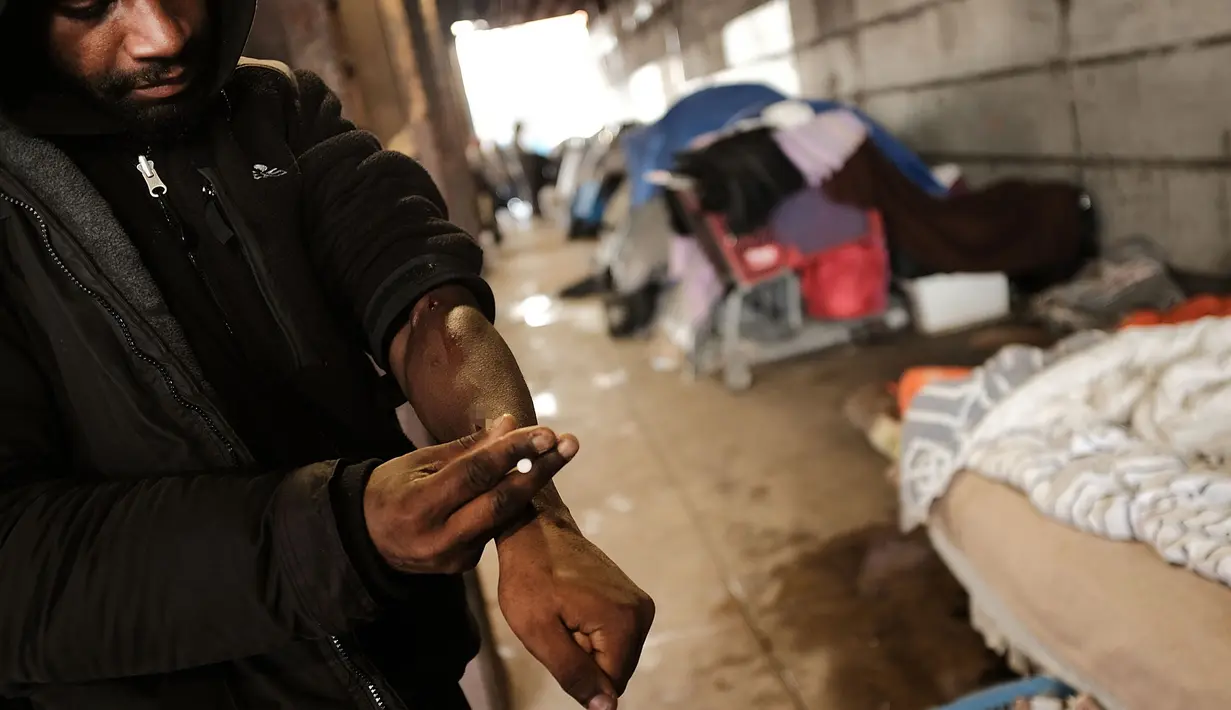 Seorang pria menggunakan heroin di bawah jembatan yang menjadi pusat penggunaan heroin di Kensington, Philadelphia (24/1). Menurut DAE Amerika Serikat, penggunaan heroin telah berlipat ganda di seluruh negeri sejak 2010. (Spencer Platt/Getty Images/AFP)