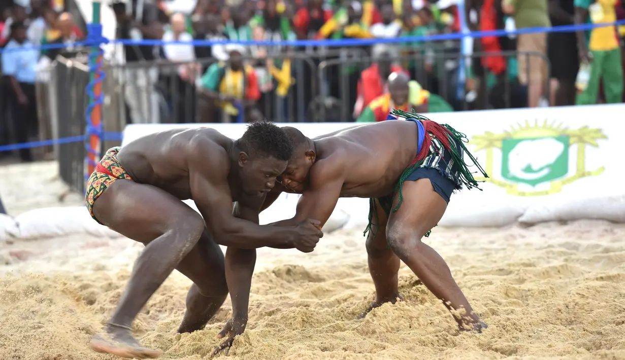 Kouame Roumaric dari Burkinabe (kanan) bertarung dengan Mouhamet Bousso dari Senegal dalam kategori 120 kg Final Gulat Wanita Tradisional selama Francophonie ke-8 di Treichville Sports Park di Abidjan pada 29 Juli 2017. (AFP Photo/Sia Kambou)