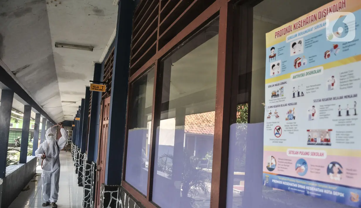 Petugas sekolah menyemprotkan disinfektan di koridor usai Pembelajaran Tatap Muka (PTM) 100 persen di SMP Negeri 9 Depok, Cipayung, Senin (24/1/2022). Penyemprotan disinfektan juga dilakukan guna mengantisipasi penyebaran Covid-19 varian Omicron yang terus meningkat. (merdeka.com/Iqbal S Nugroho)