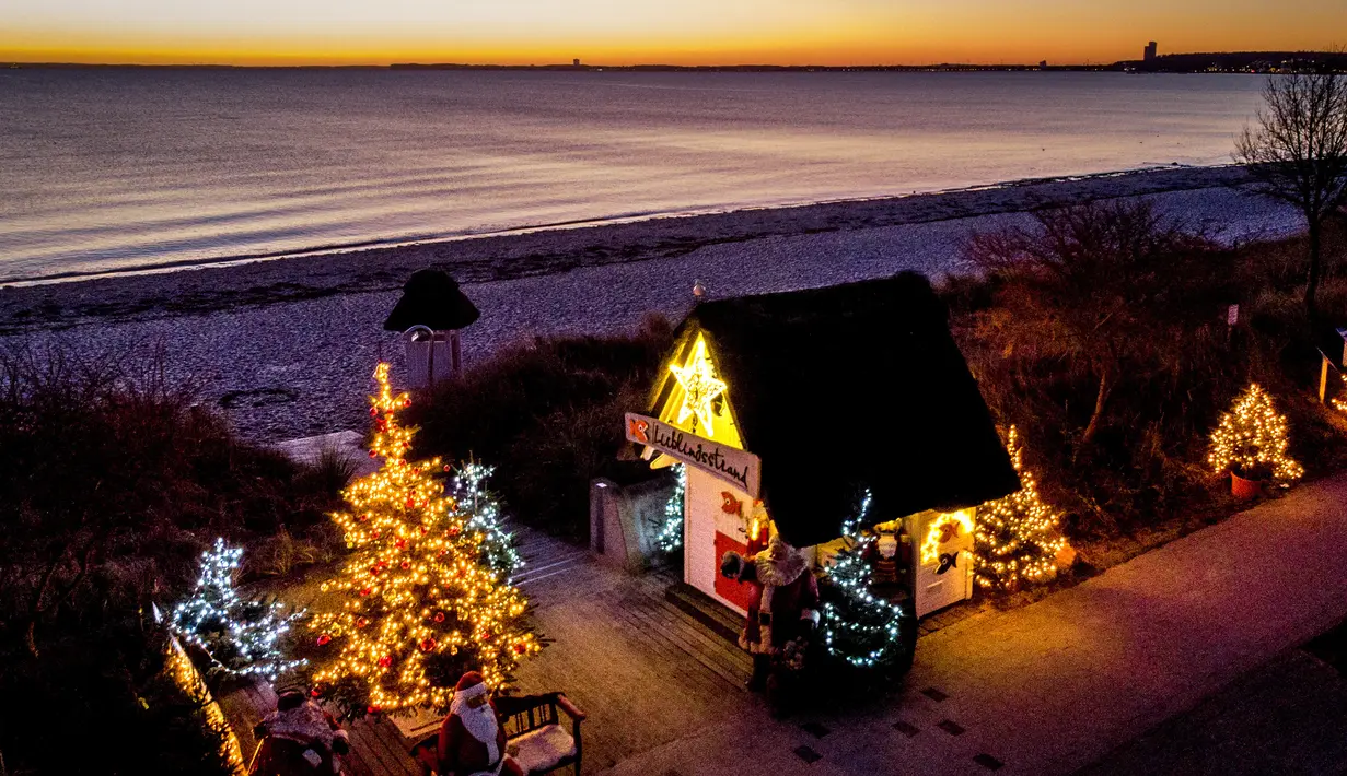 Pohon Natal dan Sinterklas menghiasi pintu masuk pantai di Haffkrug, Jerman utara, Senin (20/12/2021). (AP Photo/Michael Probst)