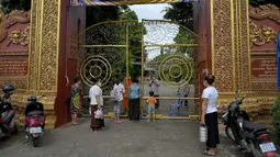 Warga antre untuk memberikan makanan dan sedekah kepada biksu Buddha saat Festival Pchum Ben (Festival Kematian) di luar pagoda di Phnom Penh, Kamboja, 24 September 2021. Pihak berwenang menghentikan perayaan Festival Kematian karena pandemi COVID-19. (TANG CHHIN Sothy/AFP)