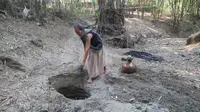 Seorang warga yang sudah tua membuat lubang di dasar sungai kering di desa Ngrandah, Kabupaten Grobogan untuk mencari sumber air. (foto: Liputan6.com / Felek Wahyu)