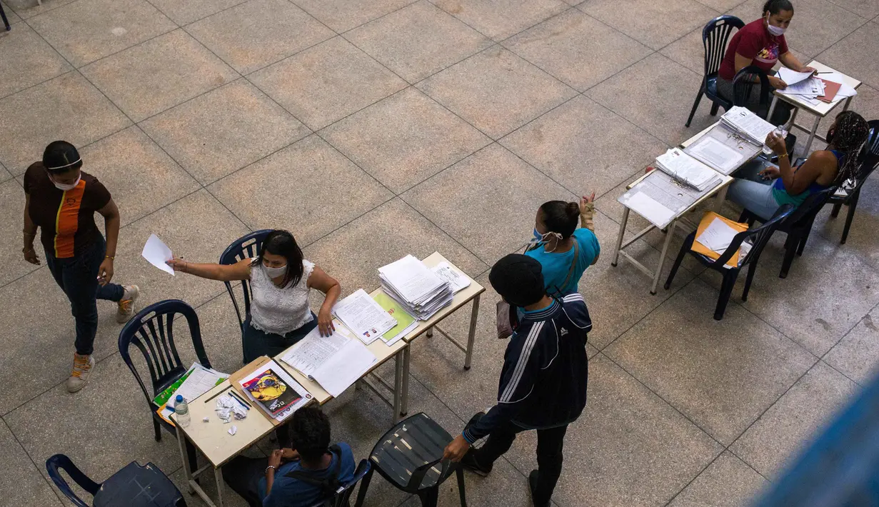 Para orang tua mendaftarkan anaknya untuk tahun ajaran baru di aula di SMU "Tito Salas" saat pendaftaran ajaran baru di Las Minas de Baruta, Caracas, 7 Oktober 2020. Di tengah pandemi, kelas dimulai lagi di Venezuela dengan siswa yang harus mencari sinyal internet di jalan. (Cristian Hernandez/AFP)