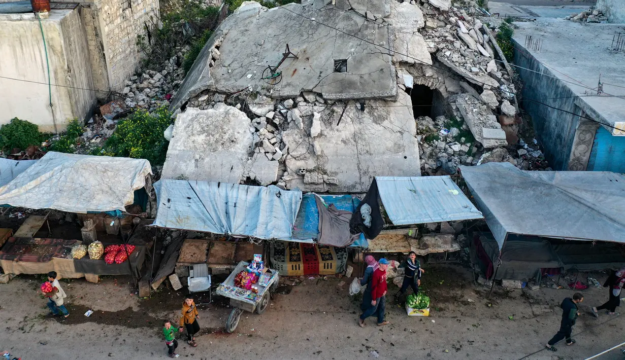 Pemandangan udara saat warga Suriah membeli produk makanan di pasar menjelang buka puasa pada hari kedua Ramadhan, di kota Ariha yang dilanda perang, di provinsi Idlib, Kamis (15/4/2021). Mereka menjalankan Ramadhan di antara lautan reruntuhan bekas konflik gencatan senjata. (Omar HAJ KADOUR/AFP)