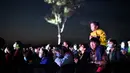 Seorang pria menggendong anaknya saat mereka menyaksikan Festival Musik Rye yang digelar selama dua hari di Beijing pada 18 Oktober 2020. (Photo by Noel Celis / AFP)