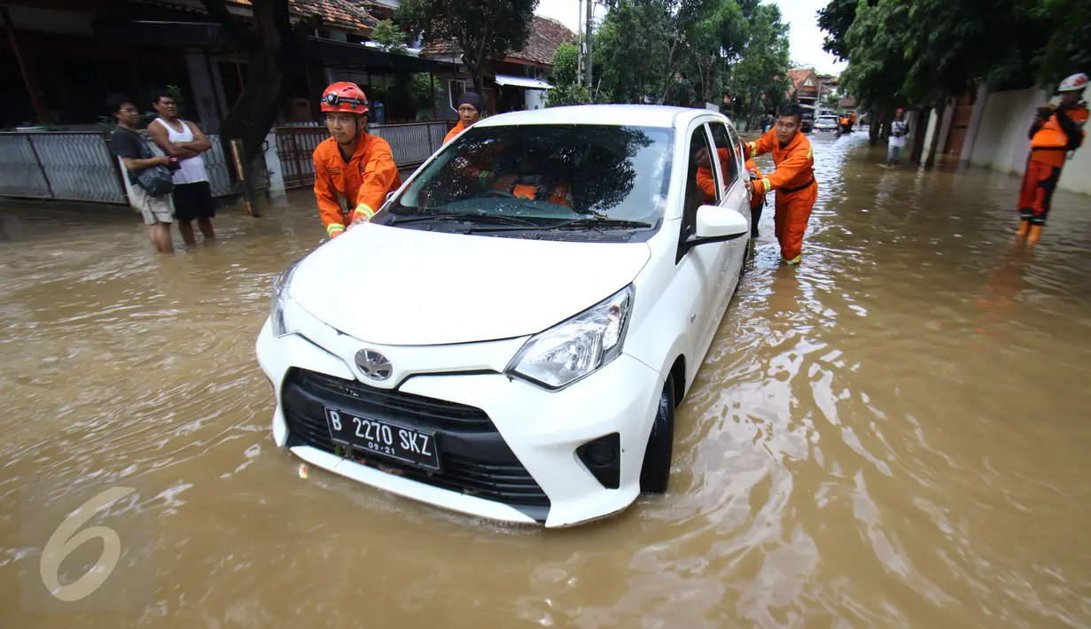 Petugas Damkar PB mendorong mobil terendam banjir di permukiman Bukit Duri, Jakarta, Kamis (16/2). Meluapnya Bendungan Katulampa, Bogor, menyebabkan permukiman kawasan Bukit Duri tergenang air dengan ketinggian 10 - 80 cm. (Liputan6.com/Helmi Afandi)