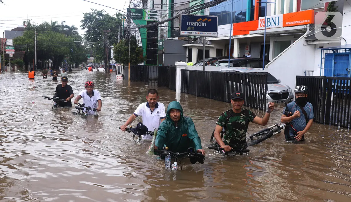 Warga melintasi banjir yang merendam Benhil, Jakarta, Selasa (25/2/2020). Hujan yang mengguyur wilayah tersebut membuat air sungai meluap sehingga menyebabkan Banjir setinggi pinggang orang dewasa. (Liputan6.com/Angga Yuniar)