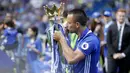 Kapten Chelsea, John Terry, mencium tropi Premier League 2016/2017 usai laga melawan Sunderland di Stamford Bridge, Minggu (21/5/2017). Terry resmi mengakhiri kiprahnya selama 22 tahun di Chelsea. (AP/Frank Augstein)