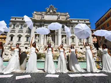 Pengantin perempuan yang mengenakan gaun pernikahan mereka melakukan flashmob saat aksi protes di Trevi Fountain, Roma, Selasa (7/7/2020). Mereka memprotes kebijakan pemerintah Italia yang masih melarang adanya acara pernikahan, meski penerapan lockdown sudah dilonggarkan. (Tiziana FABI/AFP)