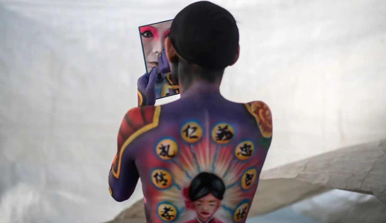 Seorang model memeriksa riasannya selama Daegu International Bodypainting Festival 2017 di Daegu, Korea Selatan, (26/8). Para model hanya menggunakan celana dalam dan plester di dadanya untuk dijadikan kanvas hidup oleh seniman seni lukis (Ed JONES / AFP)