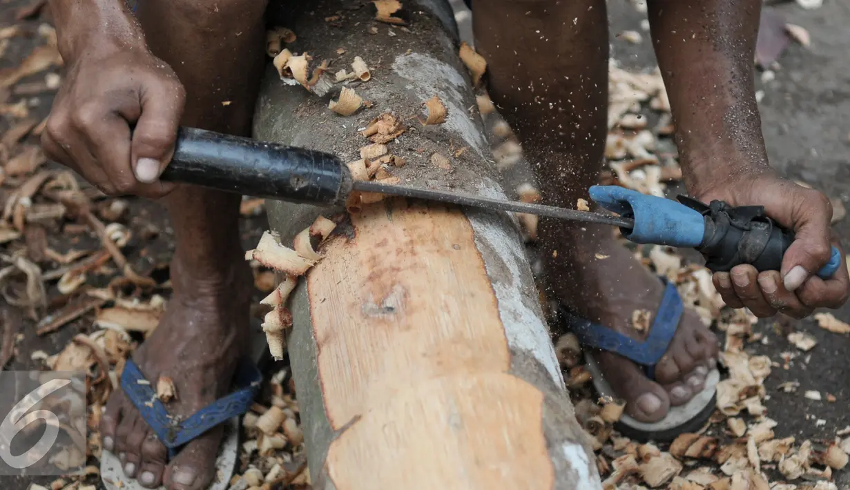 Pedagang menyerut kulit pohon pinang yang akan dijual di kawasan Manggarai, Jakarta, Selasa (9/8). Sebatang pohon pinang yang siap pakai dijual dengan kisaran harga Rp.800 ribu sampai 1juta rupiah. (Liputan6.com/Yoppy Renato)