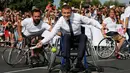 Presiden Prancis Emmanuel Macron berusaha memukul bola sambil duduk di kursi roda di Paris, Prancis (24/6). Kegiatan ini sebagai bentuk promosi Paris untuk menjadi kandidat tuan rumah Olimpiade dan Paralimpiade 2024. (AFP Photo/Alain Jocard)