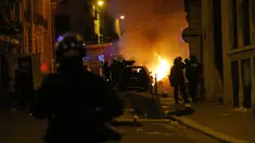 Petugas polisi Prancis menyaksikan sebuah mobil terbakar saat bentrok dengan suporter PSG di dekat jalan Champs-Elysee setelah Munchen yang dimainkan di Lisbon, Portugal di Paris, Minggu (23/8/2020) Munchen menang 1-0 atas PSG. (AP Photo/Michel