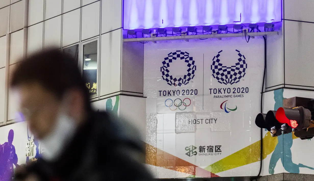 Seorang pria yang mengenakan masker melewati spanduk promosi Olimpiade Tokyo 2020 yang dijadwalkan ulang untuk musim panas ini, di Tokyo, Jepang, Kamis (28/1/2021). Olimpiade Tokyo digelar sesuai jadwal pada 23 Juli-8 Agustus 2021 setelah ditunda setahun karena corona Covid-19. (AP Photo/Hiro Komae)