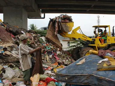 Petugas PPSU DKI Jakarta menggunakan alat berat mengangkut sampah di bawah Tol Becakayu, Cipinang Melayu, Jakarta Timur, Rabu (8/1/2020). Sampah sisa banjir tersebut selanjutnya diangkut ke TPA Bantar Gebang. (merdeka.com/Magang/Muhammad Fayyadh)