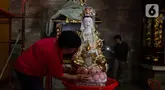 Warga membersihkan patung di Vihara Amurva Bhumi, Jakarta, Jumat (2/2/2024).  (Liputan6.com/Herman Zakharia)