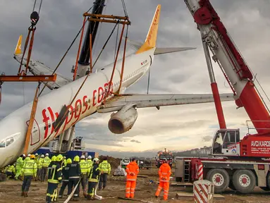 Sebuah crane mengangkat pesawat Boeing 737-800 dari maskapai Pegasus Airlines yang nyaris terperosok ke dalam laut di bandara Trabzon, Turki (18/1). Sebelumnya, pesawat itu tergelincir dari landasan pacu. (AP Photo / Turkay Albayak)