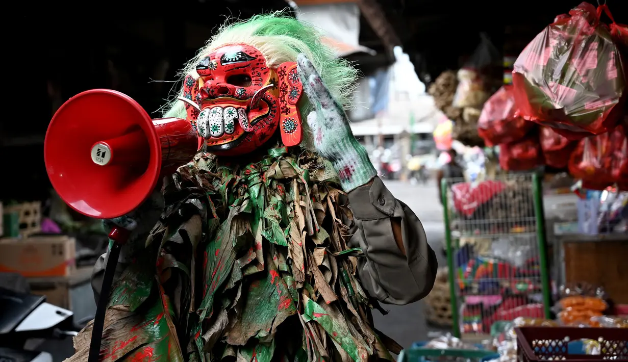 Polisi mengenakan topeng menyeramkan yang disebut "Leak" saat sosialisasi encegahan COVID-19 di pasar tradisional di Kerobokan, Denpasar, Kamis (14/5/2020). Kegiatan itu mengimbau masyarakat agar selalu mengenakan masker, rutin mencuci tangan, menjaga jarak, serta tidak mudik. (SONNY TUMBELAKA/AFP)