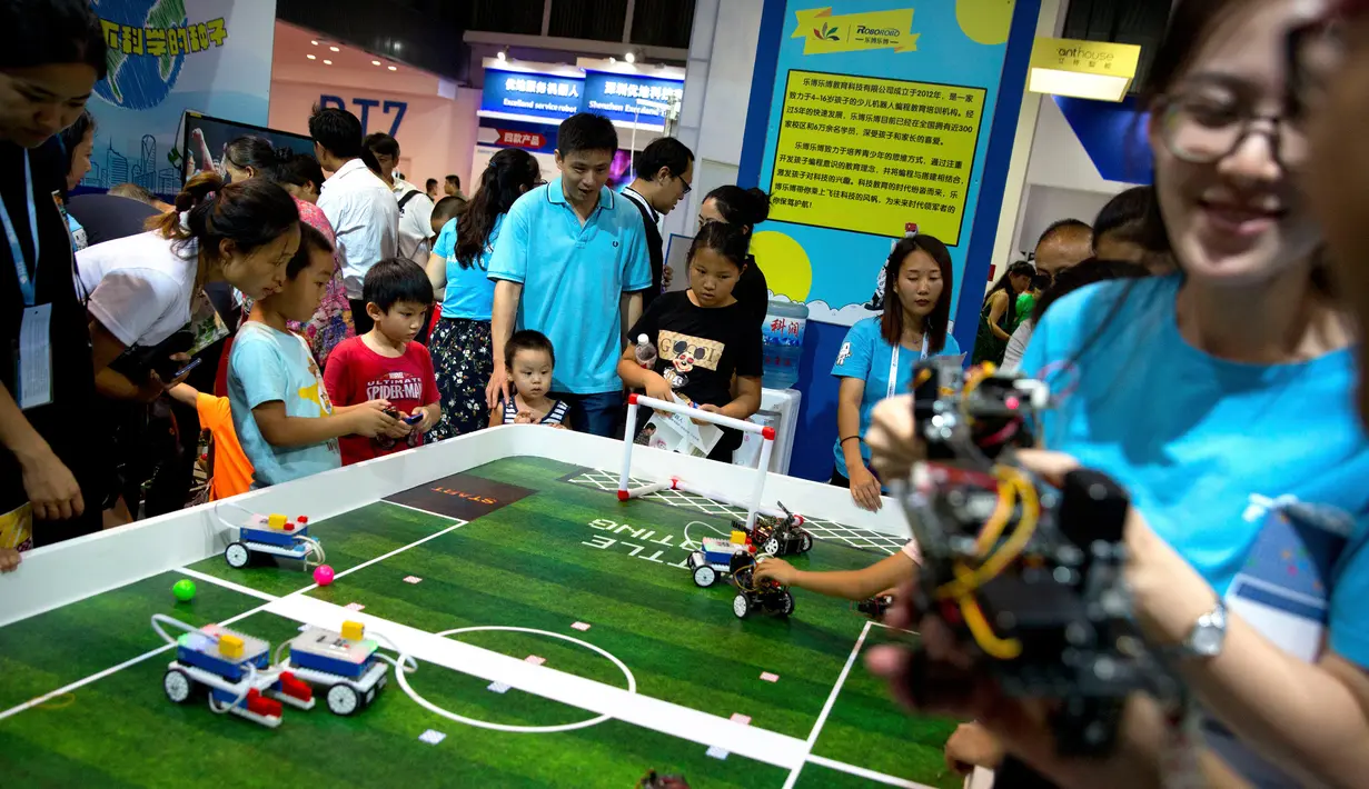 Anak-anak bermain dengan robot-robot kecil dari Roborobo di Konferensi Robot Dunia 2018 di Beijing, China, Rabu (15/8). (AP Photo/Mark Schiefelbein)