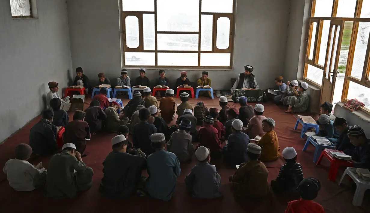 Anak-anak membaca Alquran selama bulan suci Ramadhan di sebuah masjid di pinggiran Kabul, Afghanistan, Selasa (27/4/2021).  Bulan Ramadhan menjadi momen untuk memperbanyak amalan, termasuk ketekunan menjalani tadarus Alquran. (WAKIL KOHSAR / AFP)