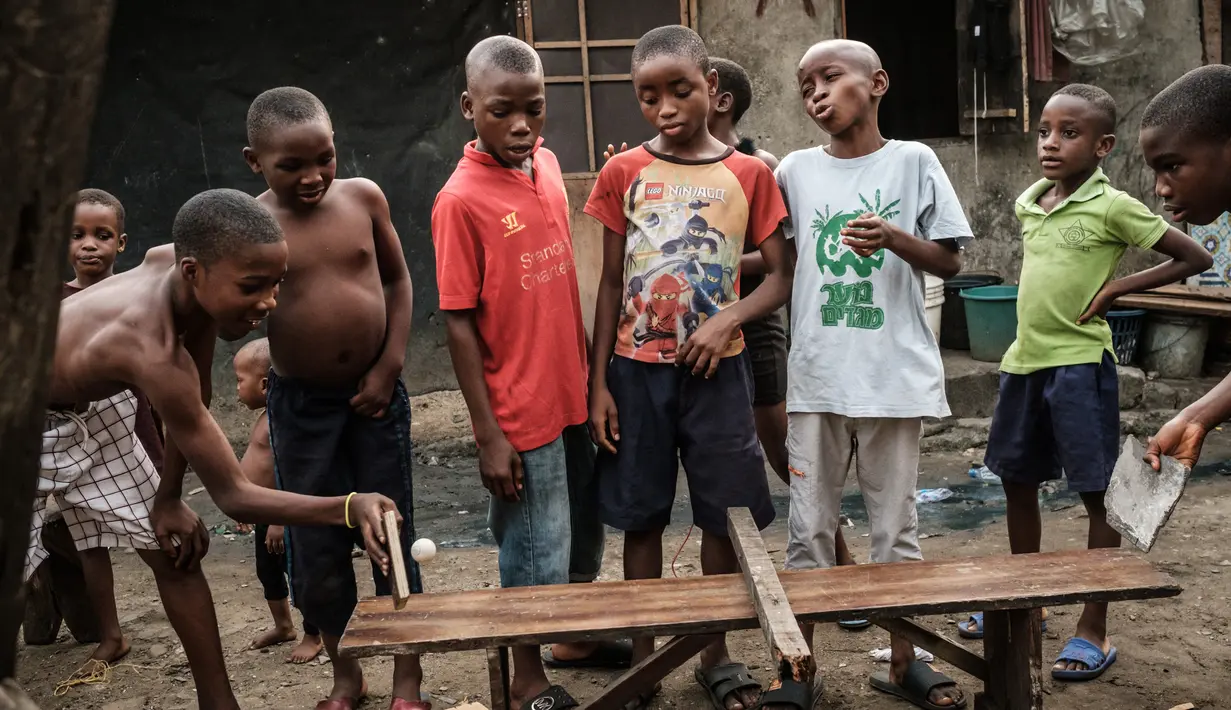 Anak-anak menggunakan potongan kayu bekas untuk bermain tenis meja di sebuah bangku di pemukiman informal Elechi Phase 3 di Port Harcourt, Nigeria selatan (14/2). (AFP Photo/Yasuyoshi Chiba)