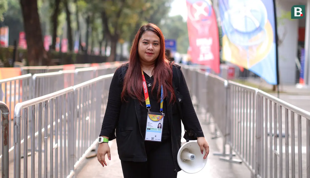 Trinia Nanda Gusti bertugas sebagai penyaring tiket di pintu masuk Indonesia Arena. Tugasnya adalah memeriksa tiket dan membantu mengarahkan penonton sesuai kategorinya. Trinia sendiri merupakan seorang mahasiswi. (Bola.com/Bagaskara Lazuardi)