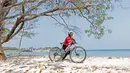 Seorang pebalap wanita Mountain Bike Cross Country Marathon mendorong sepedanya saat melintasi pasir pada Festival Pesona Tanjung Lesung 2017 di Tanjung Lesung, Banten (23/9/2017). MTB XCM tersebut menempuh jarak 48 km. (Bola.com/Nicklas Hanoatubun)
