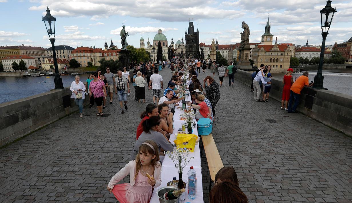 Warga menggelar makan malam di atas meja sepanjang 500 meter di jembatan bersejarah Charles Bridge di Praha, Republik Ceko, Selasa (30/6/2020). Kegiatan itu merupakan perpisahan simbolis yang digelar untuk menandai akhir dari masa krisis virus corona Covid-19 di negara tersebut (AP/Petr David Josek)