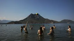 Orang-orang bermain bola voli saat menikmati cuaca cerah, laut dan matahari, sehari sebelum jam malam hari Minggu di Adrasan, 100 kilometer barat Antalya, di Mediterania Turki, Sabtu (19/6/2021).  (AP Photo/Burhan Ozbilici)