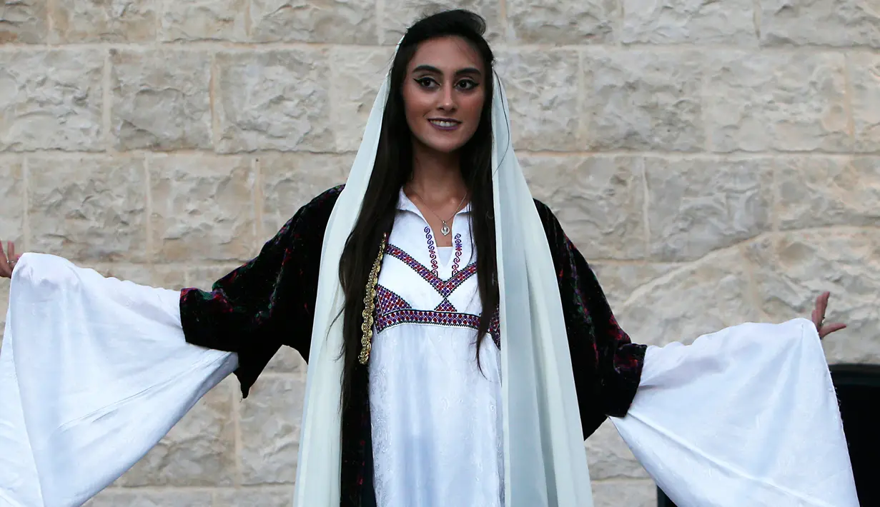Senyum seorang model saat mengikuti peragaan busana tradisional Palestina di Kota Tua Nablus, Tepi Barat, Palestina, Selasa (22/8). Peragaan busana ini sebagai salah satu upaya untuk melestarikan budaya Palestina. (AFP Photo/Jaafar Ashtiyeh)