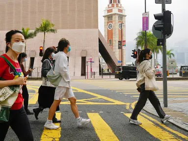Orang-orang yang memakai masker berjalan di sepanjang jalan di Hong Kong, Jumat (28/1/2022). Hong Kong memangkas masa karantina wajib bagi orang-orang yang datang dari luar negeri dari 21 menjadi 14 hari. (AP Photo/Kin Cheung)
