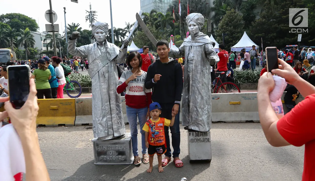 Warga sedang berfoto dengan seniman yang memerankan Pangeran Diponegoro dan Imam Bonjol saat kegiatan Car Free Day di Bundaran HI di Jakarta, Minggu, (12/11). Mereka membuka kesempatan kepada warga yang ingin foto bersama. (Liputan6.com/Fery Pradolo)