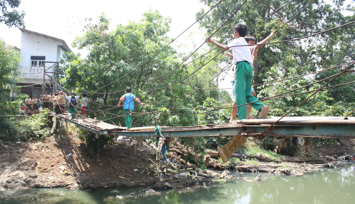 Sejumlah pelajar melintasi Kali Angke menggunakan jembatan rapuh di Kampung Cantiga, Petir, Cipondoh, Tangerang, Rabu (2/9/2015). Jembatan berusia lima tahun tersebut menghubungkan Cipondoh dan Kembangan, Jakarta. (Liputan6.com/Gempur M Surya)