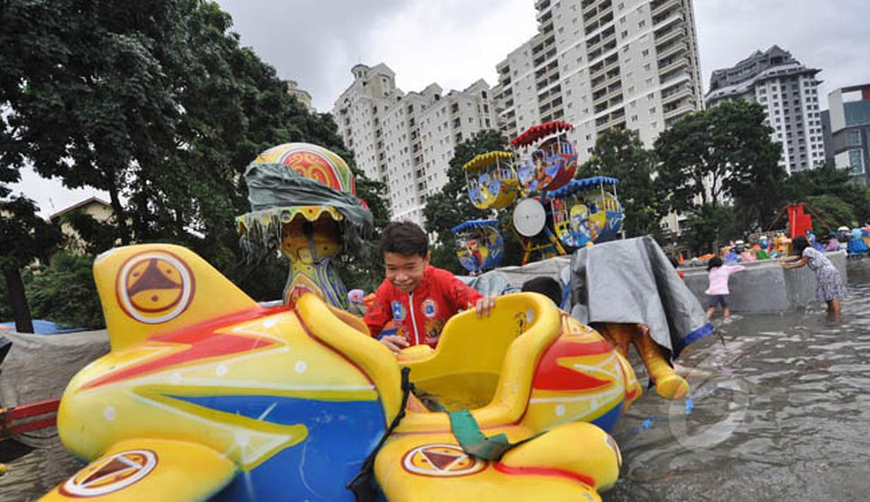 Tingginya curah hujan di wilayah Jakarta mengakibatkan sejumlah fasilitas umum ikut terendam banjir, Jakarta, Selasa (10/2). Tampak sejumlah anak bermain di lahan bermain Kemayoran yang terendam banjir. (Liputan6.com/Faizal Fanani)
