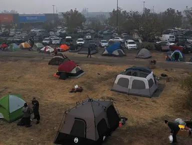 Sejumlah tenda terpasang di kamp pengungsian di sebuah lapangan di samping tempat parkir Walmart, Chico, California, AS (16/11). Akibat kebakaran yang terjadi di California sekitar 63 orang tewas. (AFP Photo/Justin Sullivan)
