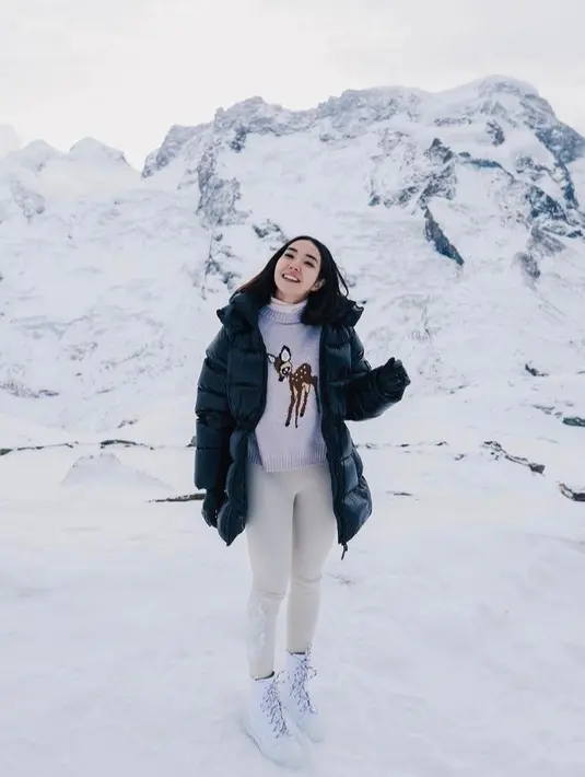 Gisella Anastasia tampil memaduka hooded puffer coat dan sweater kala berlibur di Swiss. [Instagram].