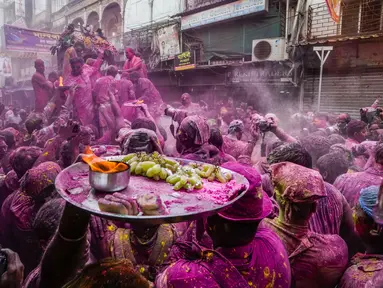 Umat Hindu dengan persembahan berjalan menuju mobil yang membawa patung dewa Krishna selama festival Holi di Kolkata, India, Minggu, 5 Maret 2023. Holi atau Festival Warna adalah festival awal musim semi yang dirayakan di India, Nepal, Bangladesh, dan negara-negara berikut yang memiliki penduduk beragama Hindu. (AP Photo/Bikas Das)