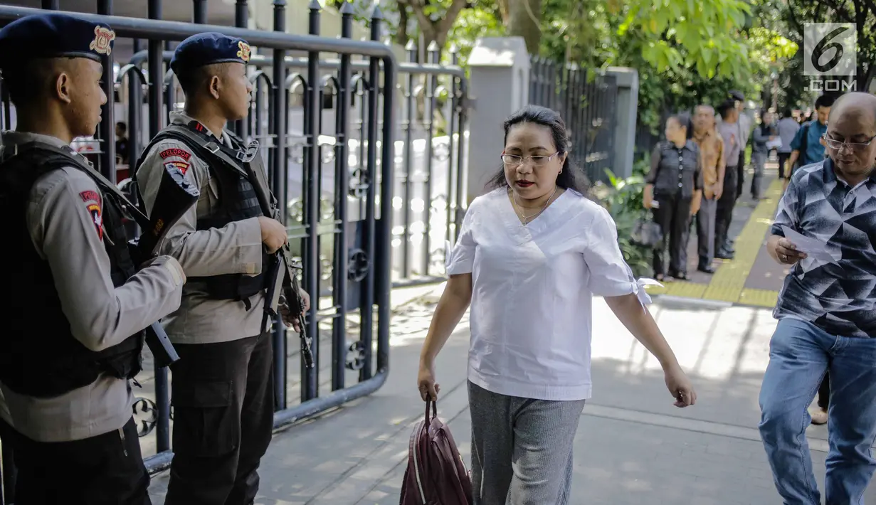 Jemaat berjalan di depan polisi bersenjata lengkap saat akan beribadah di Gereja Katedral, Jakarta, Jumat (30/3). Ibadah Jumat Agung di Gereja Katedral Jakarta dihadiri 1.200 jemaat. (Liputan6.com/Faizal Fanani)