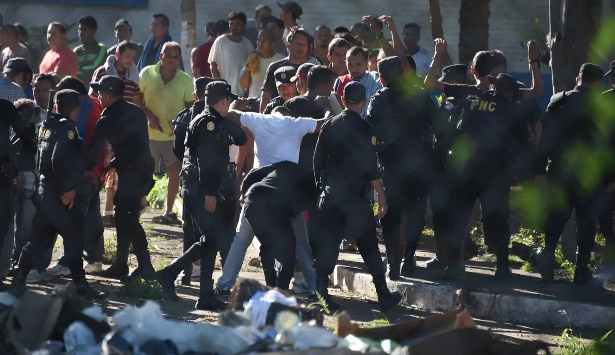 Polisi anti huru hara terlihat mengamankan sekelompok tahanan seusai terlibat kerusuhan di sebuah penjara dengan keamanan maksimum di Guatemala, Senin (30/11). 16 tahanan tewas dalam perkelahian antarnapi di penjara tersebut. (AFP Photo/JOHAN ORDONEZ)