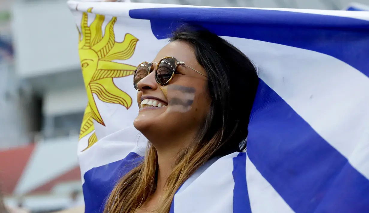 Suporter wanita Uruguay membentangkan bendera negaranya sebelum pertandingan antara Uruguay melawan Portugal pada 16 besar Piala Dunia 2018 di Stadion Fisht di Sochi, Rusia, (30/6). Uruguay berhasil mengalahkan Portugal 2-1. (AP Photo/Andre Penner)