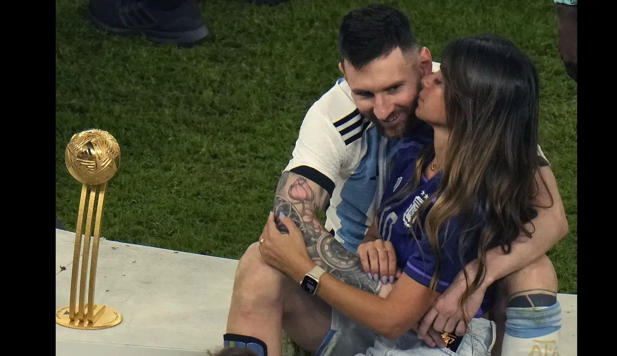 Antonela Ruccuzzo (kanan) mencium suaminya, Lionel Messi saat merayakan kemenangan Argentina di Piala Dunia 2022 setelah mengalahkan Prancis pada laga final yang berlangsung di Lusail Stadium, Qatar, Minggu (18/12/2022). Albiceleste menang 4-2 atas Prancis di babak penalti. (AP Photo/Francisco Seco)
