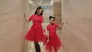 Ibu dan anak ini kembaran pakai dress tulle merah yang dipadukan sepatu boots hitam.