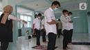 Guru yang juga satgas Covid-19 sedang melakukan pengawasan saat ibadah di SMKN 51, Jakarta, Rabu (7/4/2021). SMKN 51 melakukan uji coba masuk sekolah dan Uji Sertifikasi Kompetensi (USK) dengan protokol kesehatan yang ketat. (Liputan6.com/Herman Zakharia)
