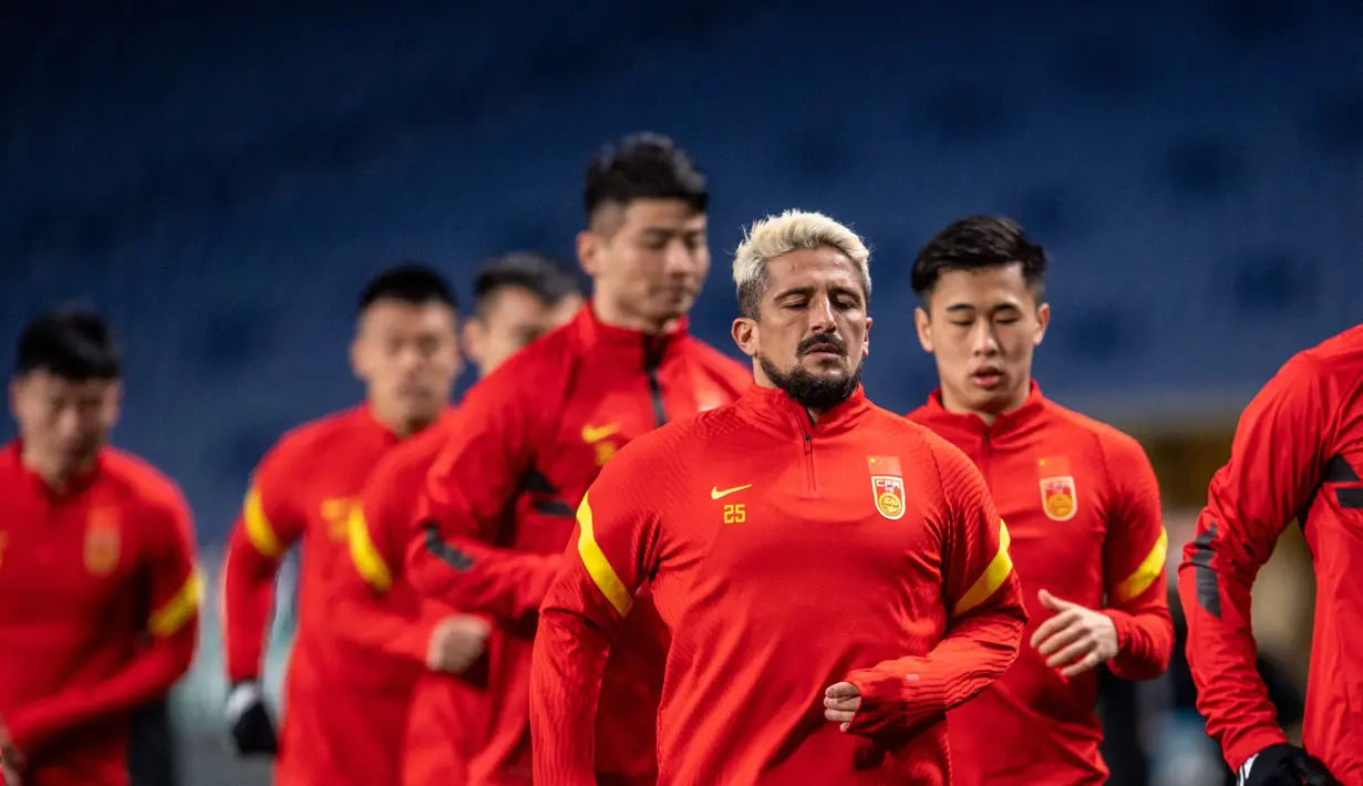 Aloisio dos Santos Goncalves dari China, juga dikenal sebagai Luo Guofu (depan) melakukan pemanasan saat mengikuti sesi latihan di Stadion Saitama, Jepang, Rabu (26/1/2022). China akan menghadapi Jepang pada Kualifikasi Piala Dunia 2022 Grup B Zona AFC. (AFP/Philip Fong)