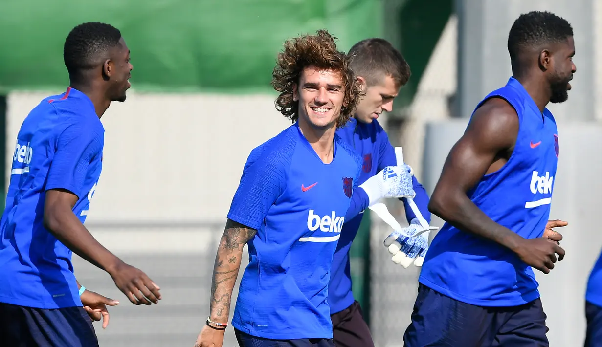 Penyerang baru Barcelona, Antoine Griezmann tertawa ketika melakukan pemanasan selama latihan pramusim pertama di Joan Gamper, Barcelona (15/7/2019). Griezmann resmi menjadi pemain Barcelona usai diboyong dari Atletico Madrid. (AFP Photo/Lluis Gene)